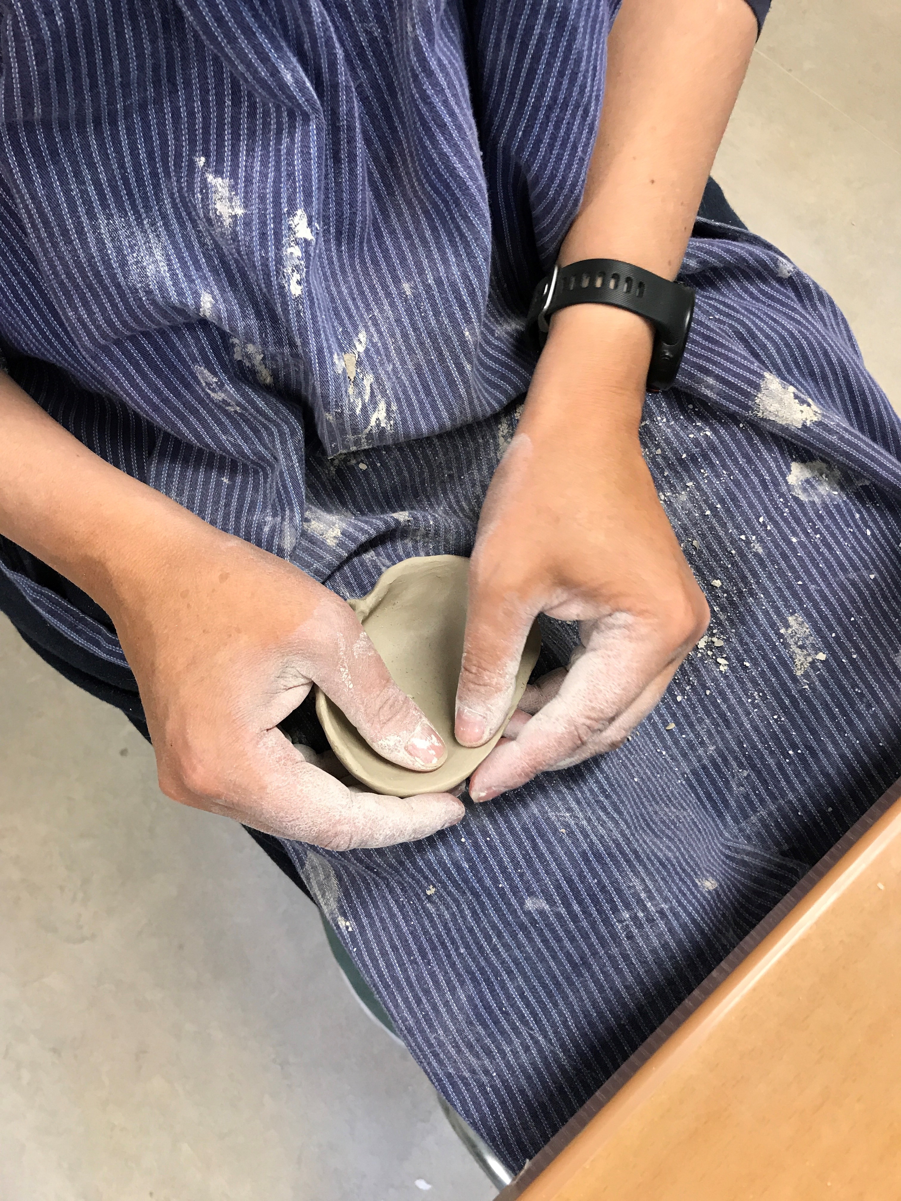 Händer som arbetar med keramik i knät