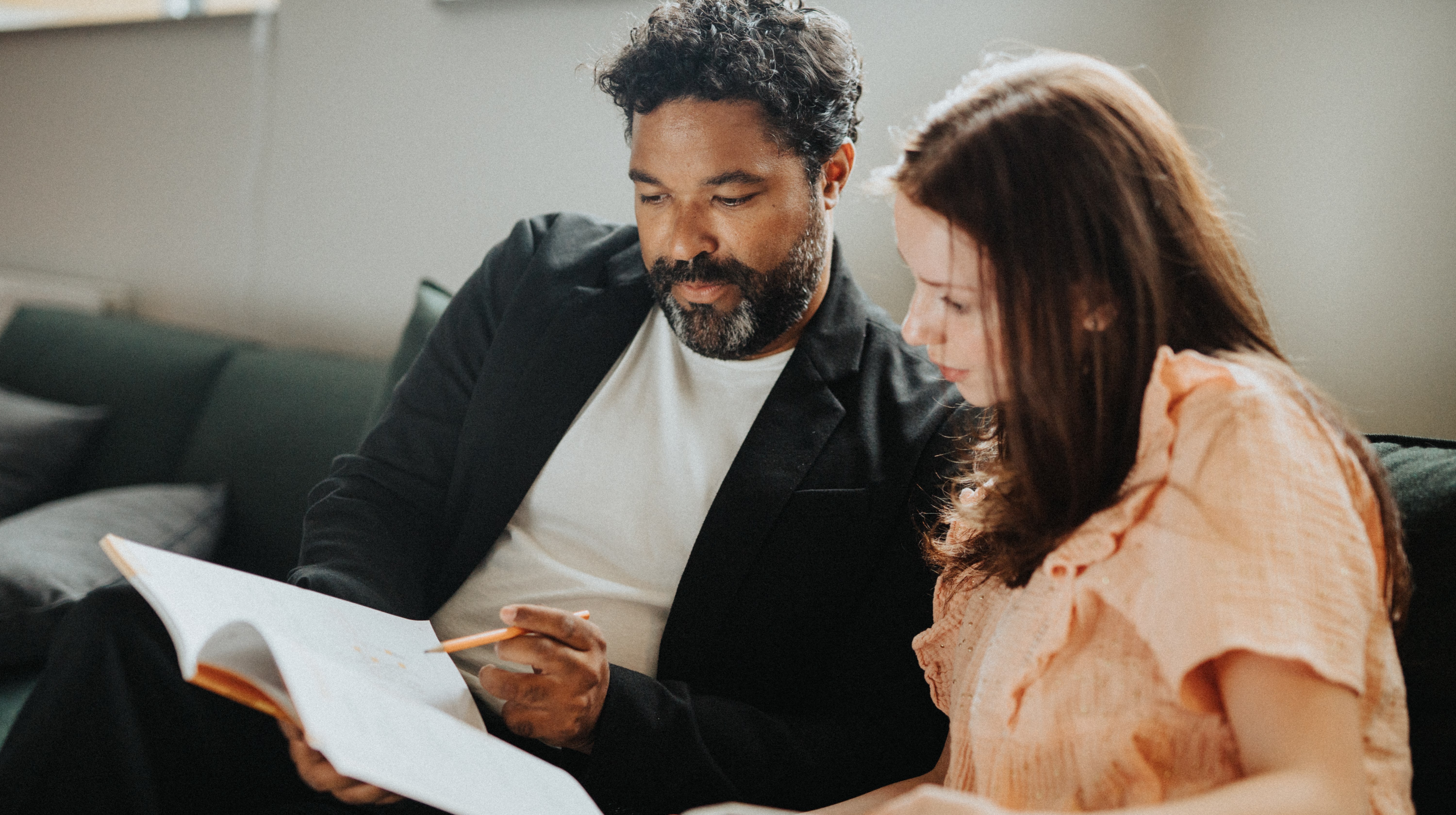 Flicka sitter med vuxen och läser