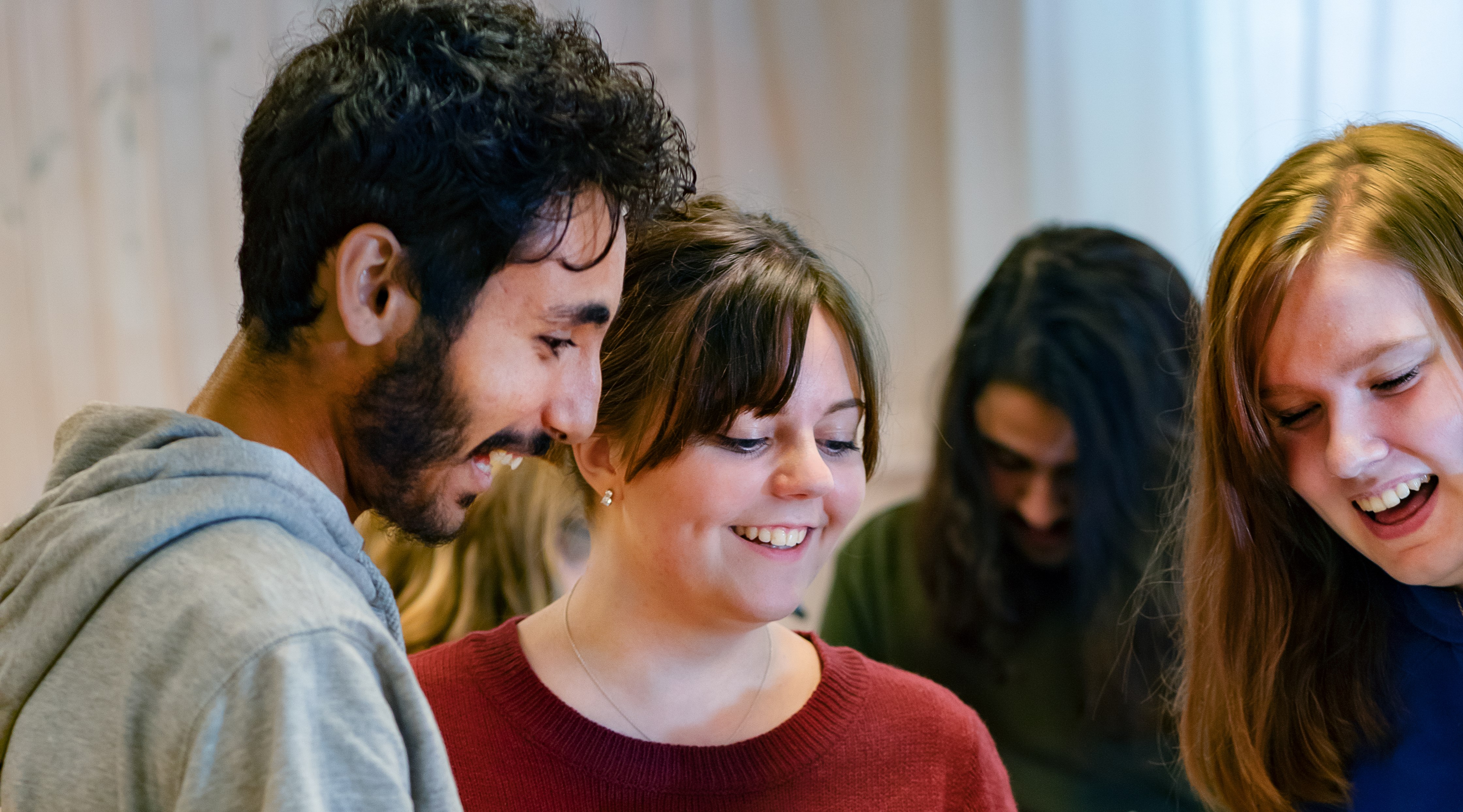 Tre stycken deltagare som tittar nedåt och ler.